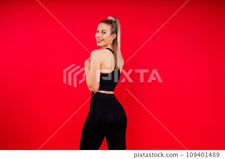 Beautiful young woman dressed in sports uniform, posing in studio on a yellow red dark background. Beautiful young woman dressed in sports uniform, posing in studio on a yellow red dark background. 109401489