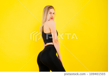 Beautiful young woman dressed in sports uniform, posing in studio on a yellow red dark background. Beautiful young woman dressed in sports uniform, posing in studio on a yellow red dark background. 109401503