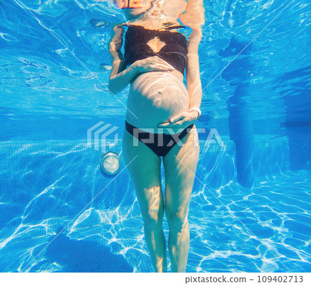 Pregnancy embraced underwater a tranquil scene as a woman tenderly hugs her belly in the pool, capturing the beauty of maternal connection Pregnancy embraced underwater a tranquil scene as a woman tenderly hugs her belly in the pool, capturing the beauty of maternal connection 109402713