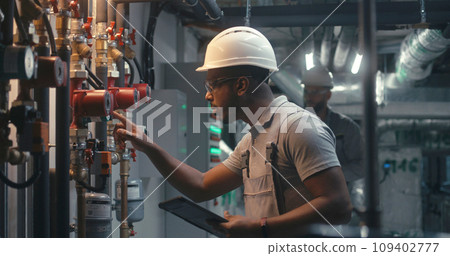 African American inspector checks pipeline system on factory 109402777