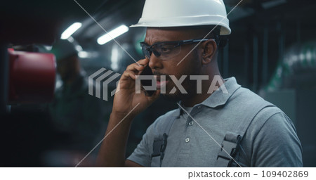 African American industrial worker talks by mobile phone African American industrial worker talks by mobile phone 109402869