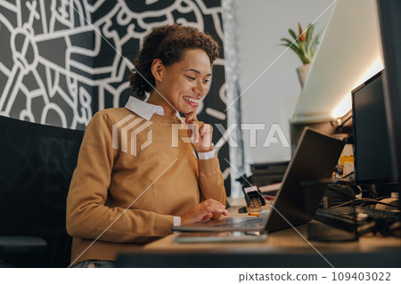 Smiling female manager using laptop while sitting on cozy office background  109403022