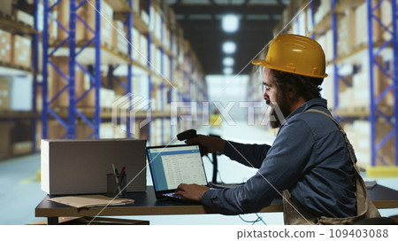 Delivery supervisor scanning barcodes for product logistics, managing delivery requirements with warehouse scanner. Factory employee reviewing parcel labels in warehouse, quality control. 109403088