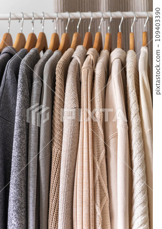 Hanger with beautiful neutral beige, white and gray clothes. Sweater sleeves. 109403390