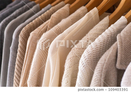 Hanger with neutral beige and white clothes on a white background. 109403391