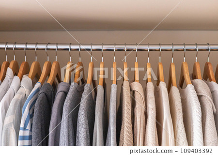 Hanger with neutral beige and white clothes on a white background. 109403392