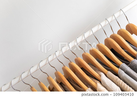 Hanger with beautiful neutral beige, white and gray clothes on a white background. Copy space. Hanger with beautiful neutral beige, white and gray clothes on a white background. Copy space. 109403410