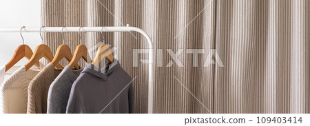 Hanger with neutral beige and white clothes on a white background. Hanger with neutral beige and white clothes on a white background. 109403414