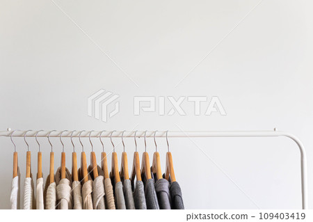 Hanger with neutral beige and white clothes on a white background. Hanger with neutral beige and white clothes on a white background. 109403419