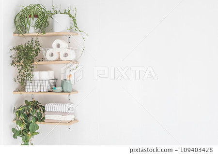 Beautiful white bathroom. Wooden shelves. Rolled towels, stacked towels and baskets.  109403428