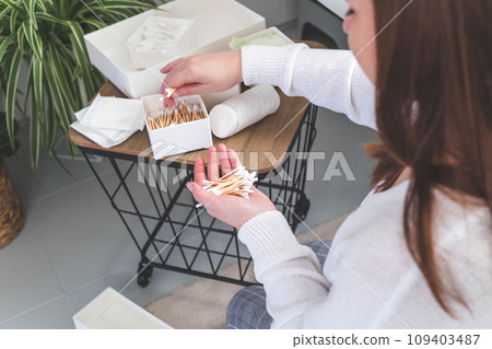 Woman organizing vanity drawer and neatly putting toiletries of cotton rounds with bamboo buds 109403487