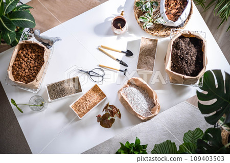 Table with fillers for houseplant transplant in boxes and paper bag gardening hobby top view 109403503