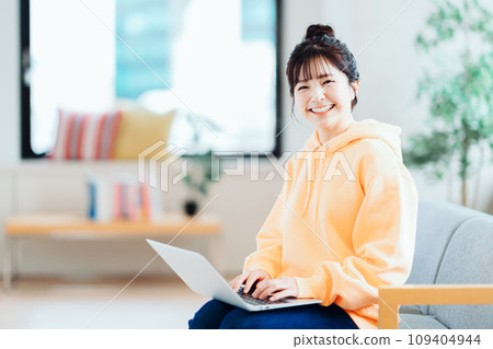 A young freelance woman operates a laptop in the living room. 109404944