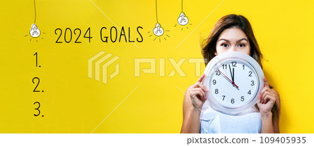 2024 goals with young woman holding a clock 2024 goals with young woman holding a clock 109405935