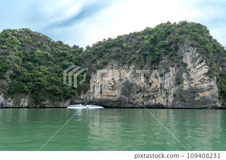 越南：一個人在奇岩怪石環繞的下龍灣劃著獨木舟，到達一個旅遊景點。 109408231