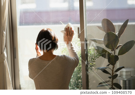 A woman in her 50s cleaning windows 109408570