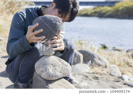 man doing rock balancing 109409174