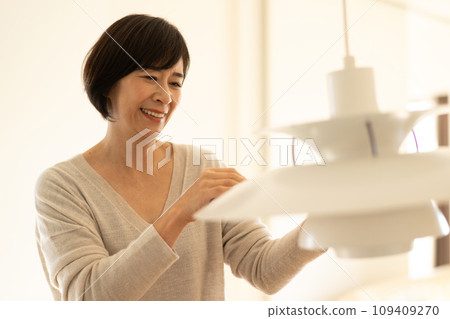 A woman cleaning lighting umbrellas and pendant lights 109409270