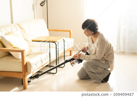 A woman cleaning the floor with a vacuum cleaner A woman cleaning the floor with a vacuum cleaner 109409487