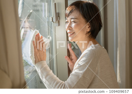 A woman in her 50s cleaning windows 109409657
