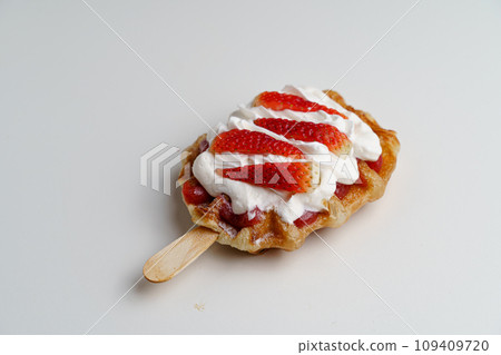 croissant waffles decorated with whipped cream, strawberries, nuts, banana and blueberries 109409720