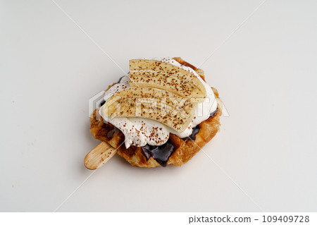 croissant waffles decorated with whipped cream, strawberries, nuts, banana and blueberries 109409728