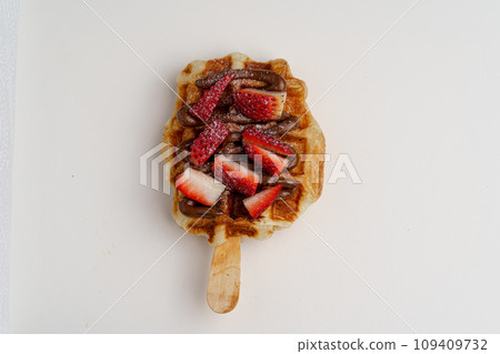 croissant waffles decorated with whipped cream, strawberries, nuts, banana and blueberries 109409732