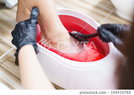 Beautiful Asian young woman having a paraffin foots and hands spa at beauty - spa shop. Foot and hand paraffin treatment. Beautiful Asian young woman having a paraffin foots and hands spa at beauty - spa shop. Foot and hand paraffin treatment. 109410768