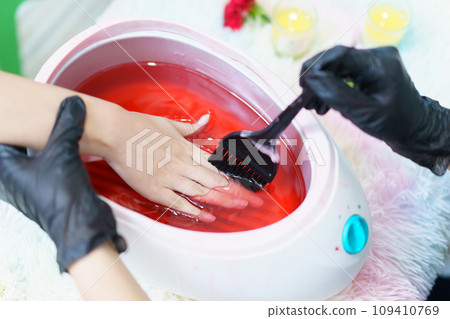 Beautiful Asian young woman having a paraffin foots and hands spa at beauty - spa shop. Foot and hand paraffin treatment. 109410769