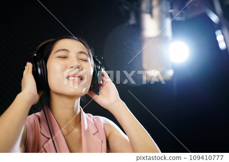 Asian professional singers recording in audio recording studio, professional male and female singer or vocalist singing in the studio. 109410777