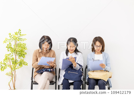 Woman filling out a clipboard in the waiting room 109412179
