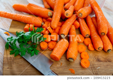 Pile of fresh sweet carrots on wooden cutting board Pile of fresh sweet carrots on wooden cutting board 109413223