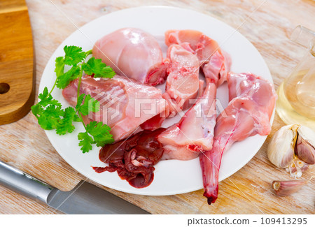 Chopped fresh raw rabbit on plate with greens, garlic and spices 109413295