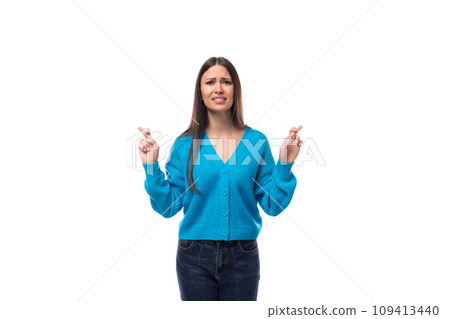 young beautiful European brunette woman dressed in a blue cardigan crossed her fingers in 109413440