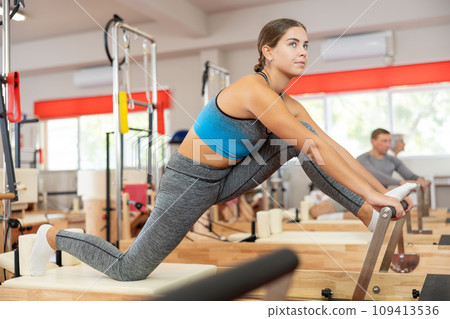 Girl performs exercise on reformer to improve coordination, balance, and posture Girl performs exercise on reformer to improve coordination, balance, and posture 109413536