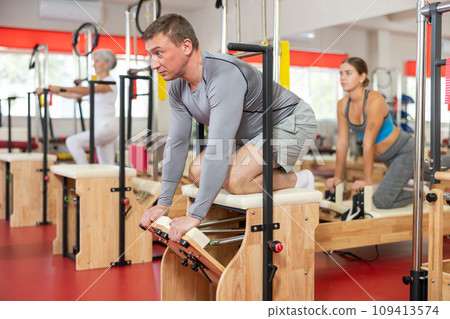 Man does gymnastics in gym and performs bends and stretches on wunda chair 109413574
