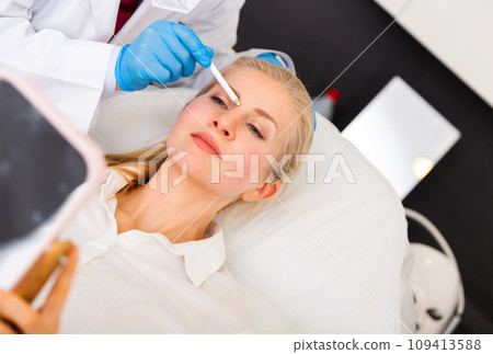 Young woman on doctor-cosmetologist's appointment Young woman on doctor-cosmetologist's appointment 109413588
