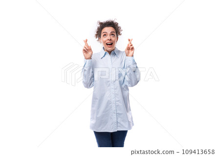 pretty young curly business woman in blue shirt crossed fingers on white background with copy space 109413658