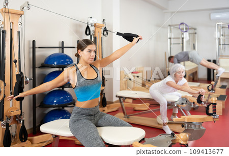 Young woman training her arms using straps Young woman training her arms using straps 109413677