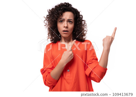 young surprised brunette woman dressed in an orange shirt on a white background young surprised brunette woman dressed in an orange shirt on a white background 109413679