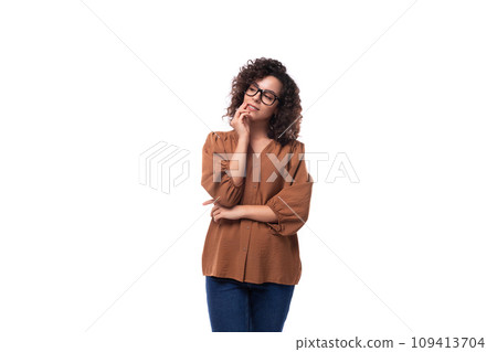 young well-groomed caucasian woman with curly black hair dressed in a brown blouse is brainstorming 109413704