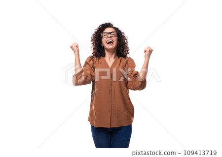 portrait of a cheerful young caucasian curly brunette woman dressed in a beautiful brown shirt 109413719