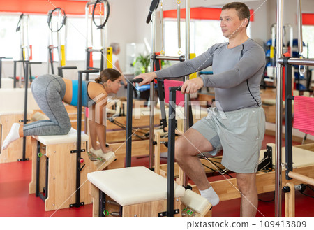 Man does gymnastics in gym and performs bends and stretches on wunda chair Man does gymnastics in gym and performs bends and stretches on wunda chair 109413809