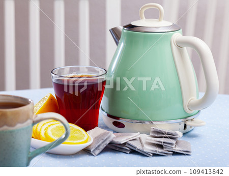 Modern electric kettle, cup and lemon on table in kitchen 109413842
