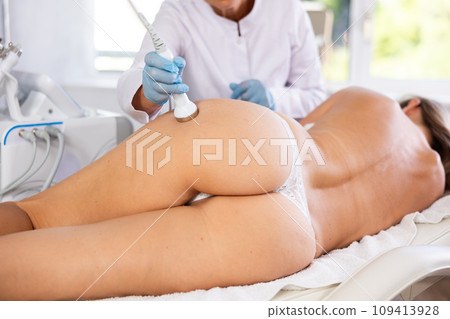 Aesthetician administering high frequency ultrasound procedure on buttocks of female patient Aesthetician administering high frequency ultrasound procedure on buttocks of female patient 109413928