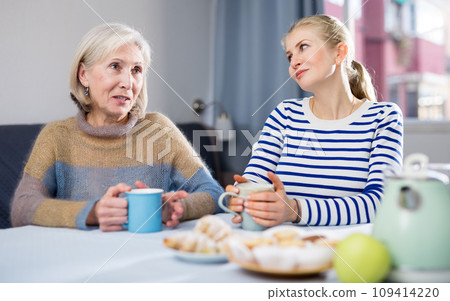 Mature mother and her adult daughter drink tea and chat Mature mother and her adult daughter drink tea and chat 109414220