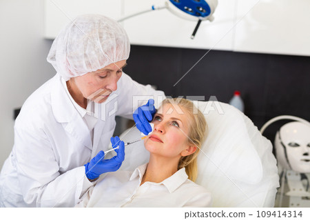 Cosmetologist doing botulotoxin injections for young woman 109414314