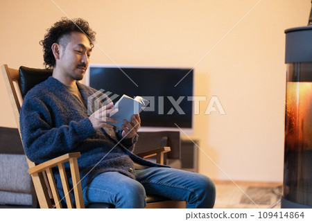 一個男人在房間壁爐旁的安樂椅上放鬆 109414864