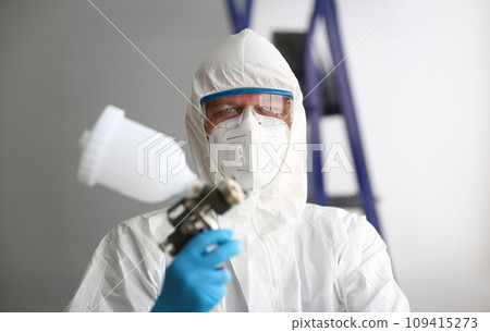 Workman hold in arm airbrush gun wearing protective suit 109415273