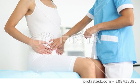 Hands of gynecologist lie on patient's stomach in clinic closeup Hands of gynecologist lie on patient's stomach in clinic closeup 109415383